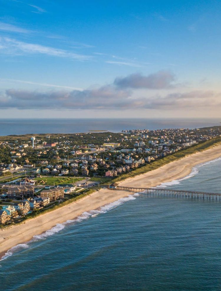 Aerial view of the coastline, highlighting the sea, sandy beaches, sky, and buildings, creating a beautiful and expansive landscape.