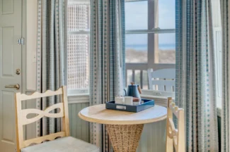 Tea set in a cozy corner of the Sanderling room, featuring a small table and two wooden chairs.