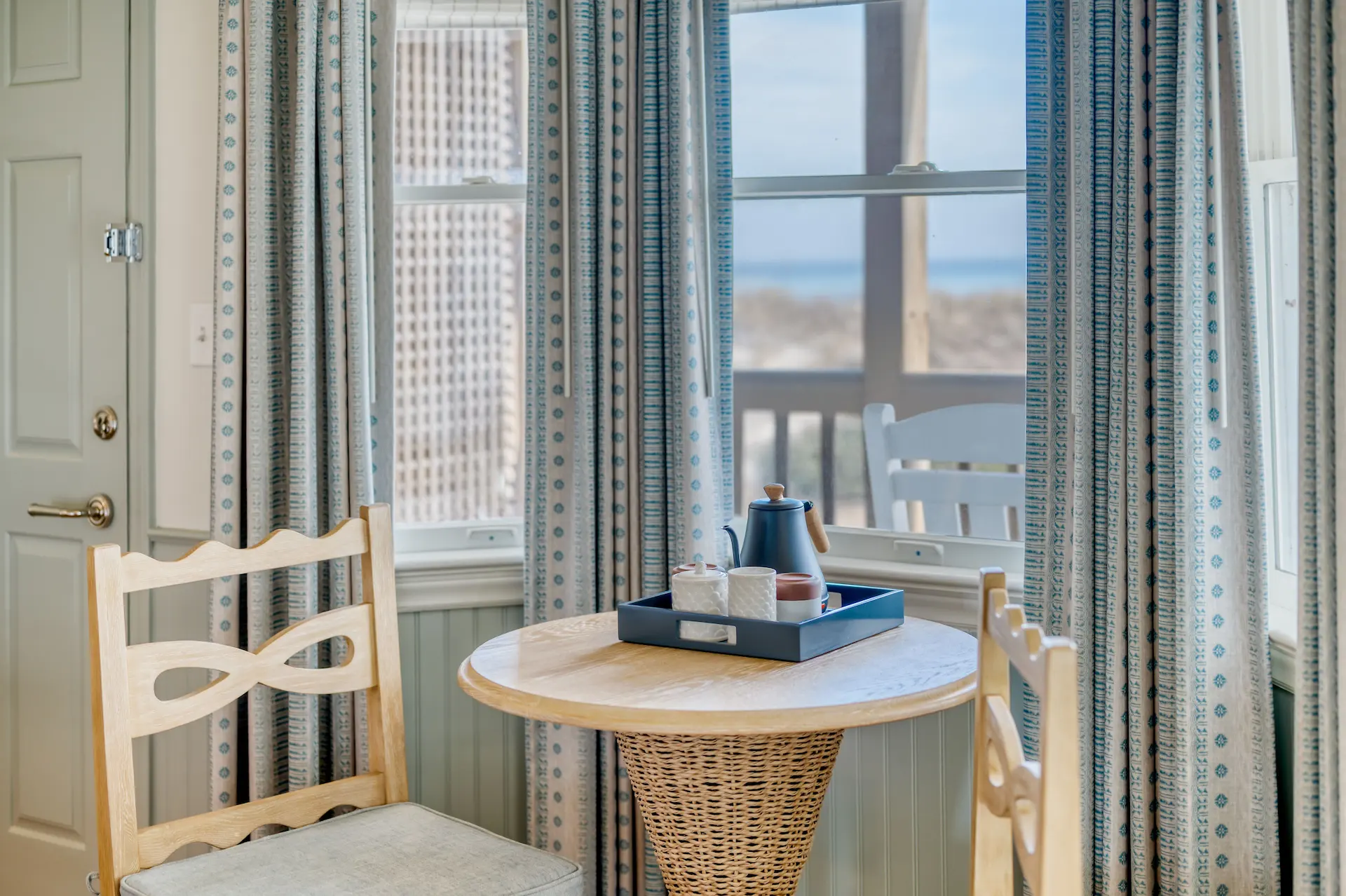 Tea set in a cozy corner of the Sanderling room, featuring a small table and two wooden chairs.