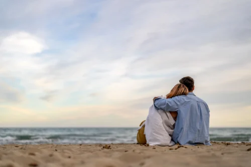 Couple on the beach watching the waves, part of The Sanderling Romance Retreat offer.