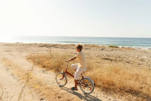 A child riding a rented bicycle along a scenic trail near the coast, enjoying the fresh air and beautiful surroundings.