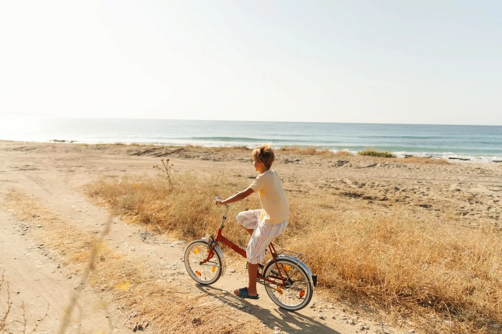 A child riding a rented bicycle along a scenic trail near the coast, enjoying the fresh air and beautiful surroundings.