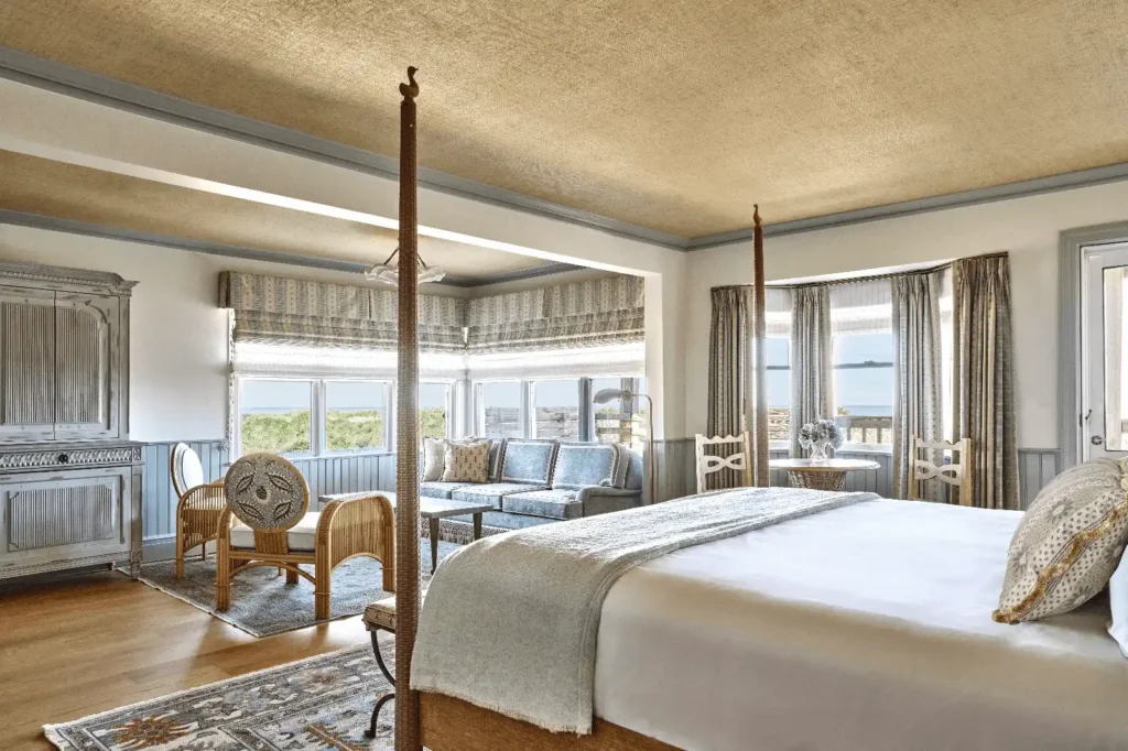 Spacious and bright room surrounded by windows with sea views, decorated in soft pastel blue tones and wood accents.