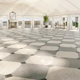 Spacious and bright event room with black and white tiles and green plants.