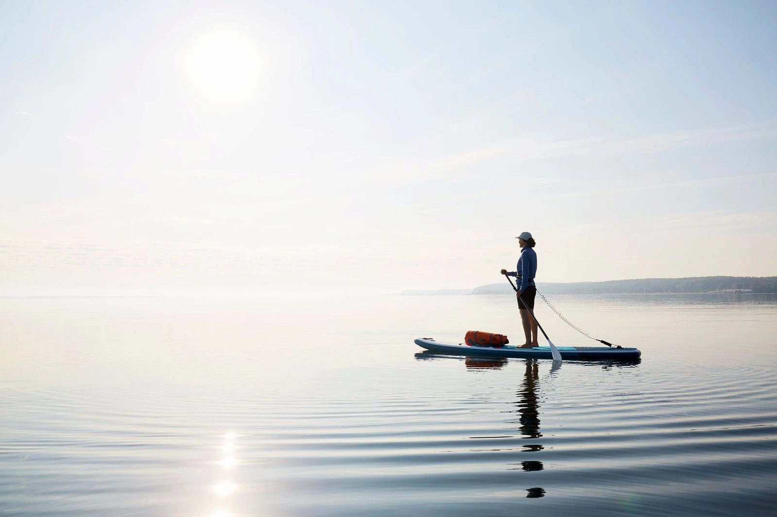 A woman peacefully practicing paddleboarding, enjoying the calm waters, thanks to the convenient Water Sport Rentals available.