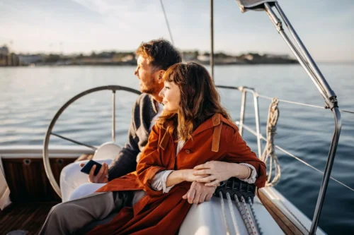 A couple enjoying a peaceful sail on a rented boat, taking in the beautiful views of the Outer Banks from the sea.