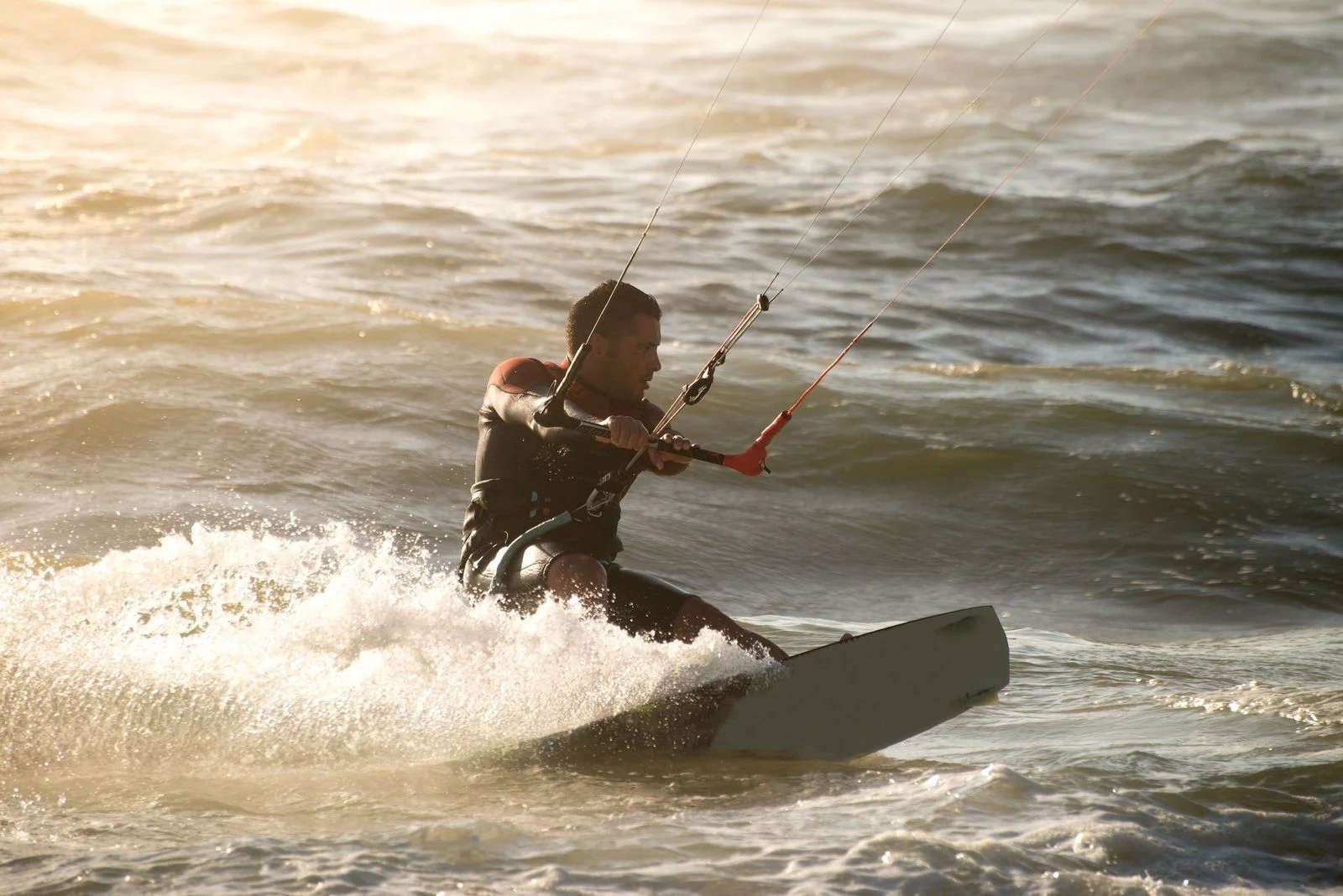 A man gliding over the waves, harnessing the wind as he enjoys an exhilarating kiteboarding session on the beach.