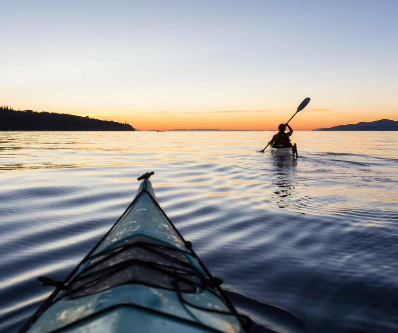 Two people enjoying boat sports, gliding across the water as the sun sets, creating a perfect golden-hour adventure.