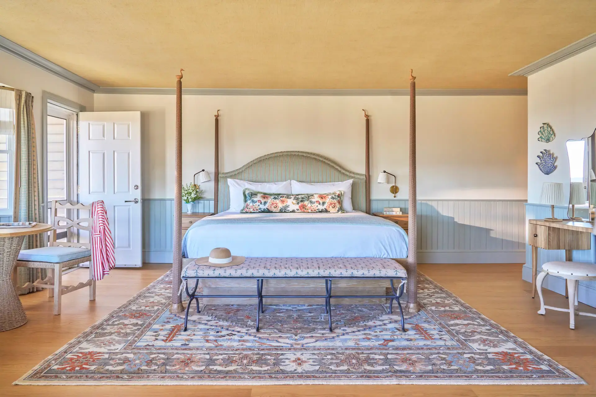 Room at The Sanderling Resort decorated in soft pastel blue tones with geometric rugs and wooden furniture.